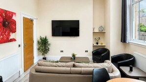 A modern living room with a sofa, chairs, a TV, and a dining table. - Large Flat in Edinburgh 4/1 (Edinburgh)