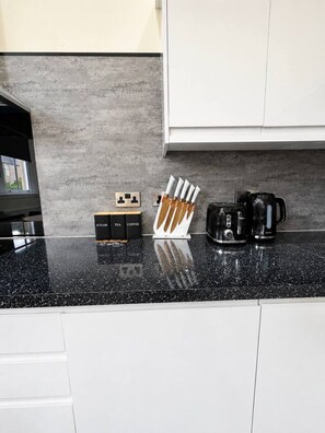 A kitchen counter with a coffee maker, a knife block, and sugar, tea, and coffee boxes. - Large Flat in Edinburgh 4/1 (Edinburgh)