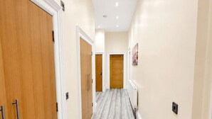 A hallway with wooden doors, a radiator, and a light switch on the wall. - Large Flat in Edinburgh 4/1 (Edinburgh)