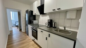 A modern kitchen with white cabinets, a stainless steel sink, a microwave, and a coffee maker. - HomeBase with a kitchen and 5 single beds, centrally located (Krefeld)