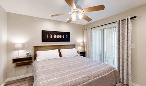 A bedroom with a bed, two bedside tables, a ceiling fan, a wall-mounted artwork, and a window with curtains. - NEW Desert Gem | Spacious 2BR Tucson Getaway (Tucson)