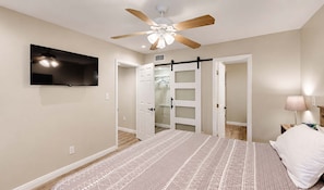 A bedroom with a bed, a ceiling fan, a TV, and a walk-in closet. - NEW Desert Gem | Spacious 2BR Tucson Getaway (Tucson)