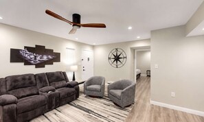 A modern living room with a ceiling fan, a large wall-mounted chessboard, and a compass wall decoration. - NEW Desert Gem | Spacious 2BR Tucson Getaway (Tucson)