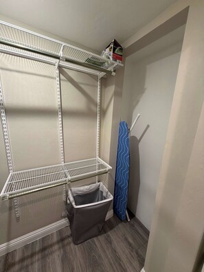 A laundry room with metal shelving, a laundry basket, and a blue towel rack. - NEW Desert Gem | Spacious 2BR Tucson Getaway (Tucson)