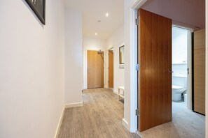 A hallway with a wooden door leading to a bathroom.