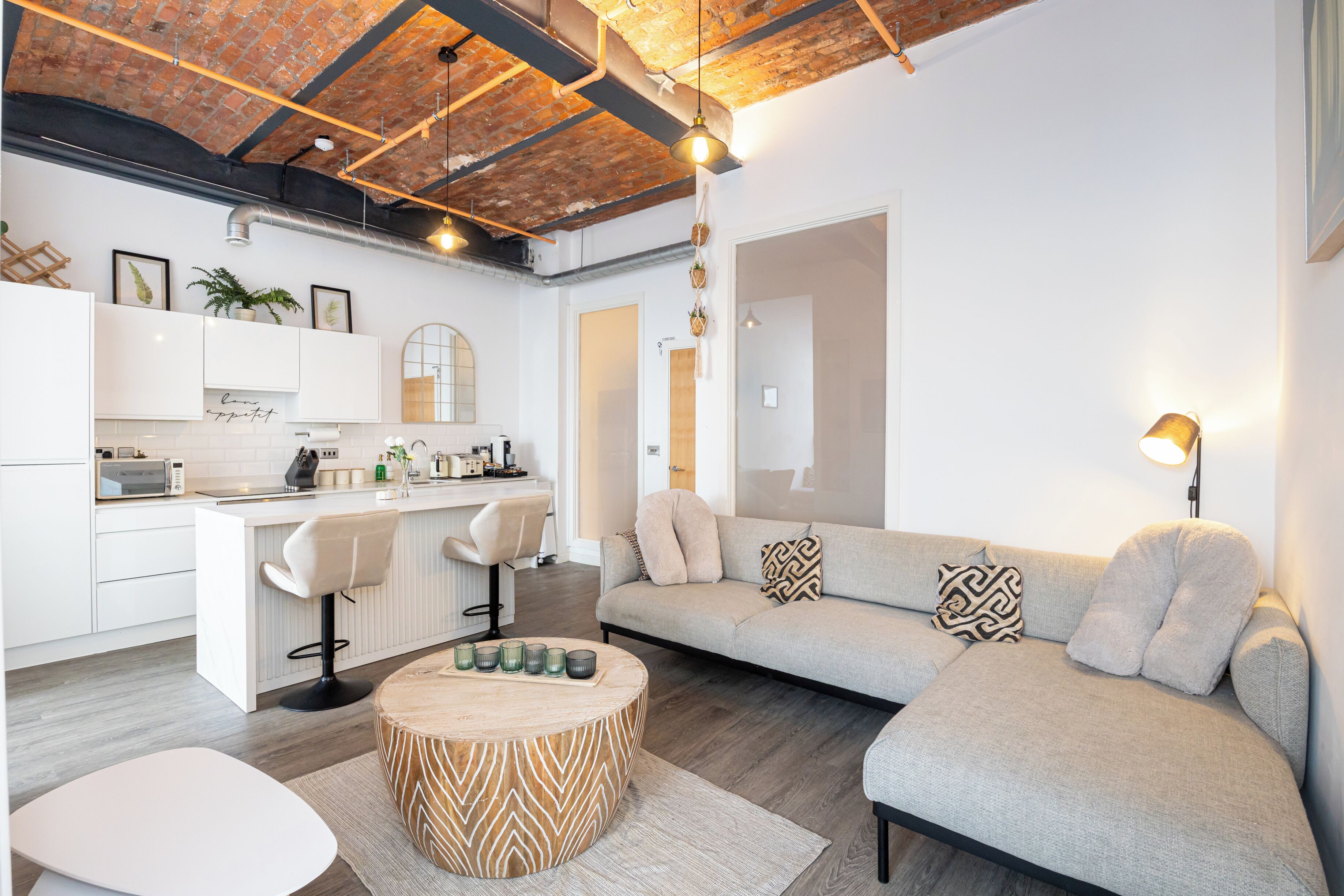A modern living space with a kitchen, a dining area, and a seating area with a sofa and a coffee table.