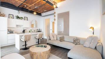 A modern living space with a kitchen, a dining area, and a seating area with a sofa and a coffee table.