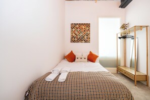A bedroom with a bed, pillows, a mirror, and a wall art piece.