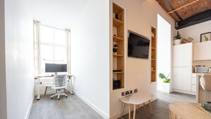 Une pièce moderne et bien éclairée, équipée d’un bureau, d’une chaise et d’étagères.