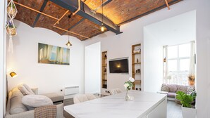 Un salon moderne avec un îlot en marbre, un canapé, un téléviseur et une bibliothèque.