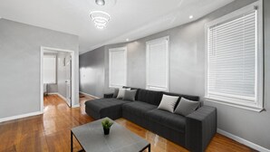 Ein modernes Wohnzimmer mit einem Ecksofa, einem Couchtisch und einer Deckenleuchte.