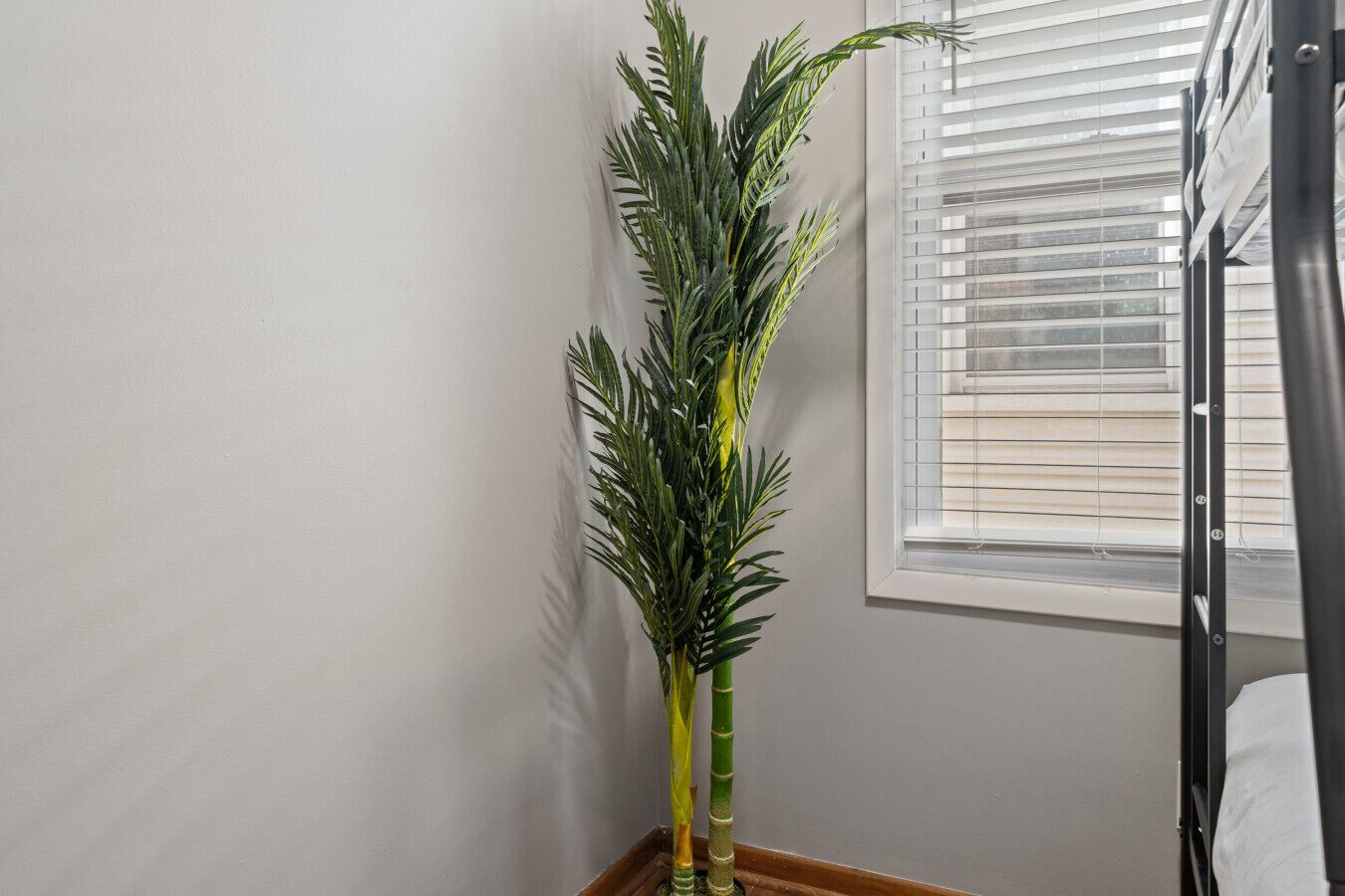 Um quarto com janela, cama e um vaso de planta.