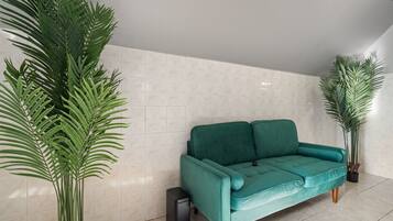 A teal sofa in a room with tiled walls and large green plants.