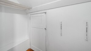 Uma porta branca com design simples, uma pequena janela e uma tomada elétrica fixada na parede.