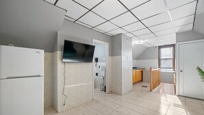 Una cocina con refrigerador, microondas y un televisor de pantalla plana montado en la pared.