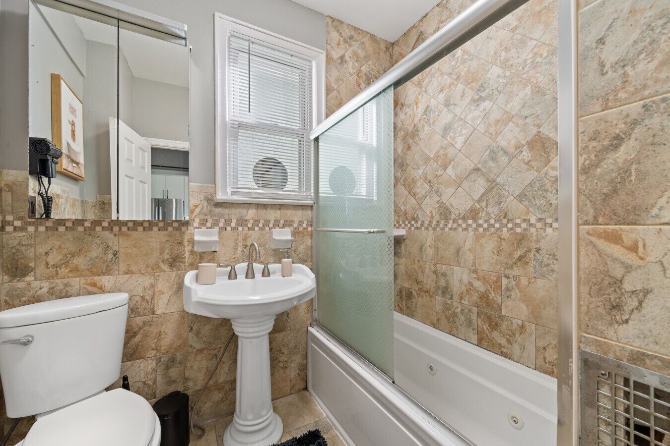 A bathroom with a pedestal sink, toilet, and a glass shower enclosure.