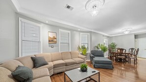 Amplia sala de estar con sofá modular, una mesa de centro y un comedor con muebles de madera.