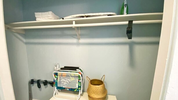 Ein Schrank mit Regalen, einem kleinen Tisch und einem Korb.