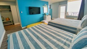 Ein Zimmer mit zwei Betten, einem Fernseher, einem Deckenventilator und einem Balkon mit Blick.
