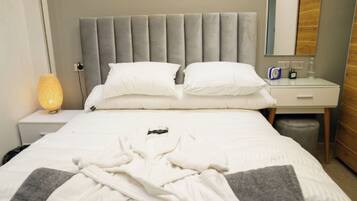 Une chambre d’hôtel avec un lit, une lampe de chevet, une table de nuit, un miroir et un mur en bois.