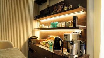 Une chambre d’hôtel avec un bureau en bois, une machine à café et une étagère contenant divers objets.