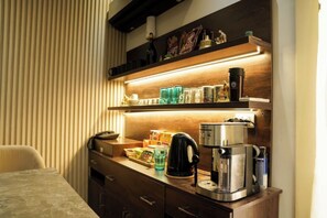 Une chambre d’hôtel avec un bureau en bois, une machine à café et une étagère contenant divers objets.