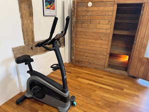 An exercise bike in a room with wooden flooring and a wooden door.