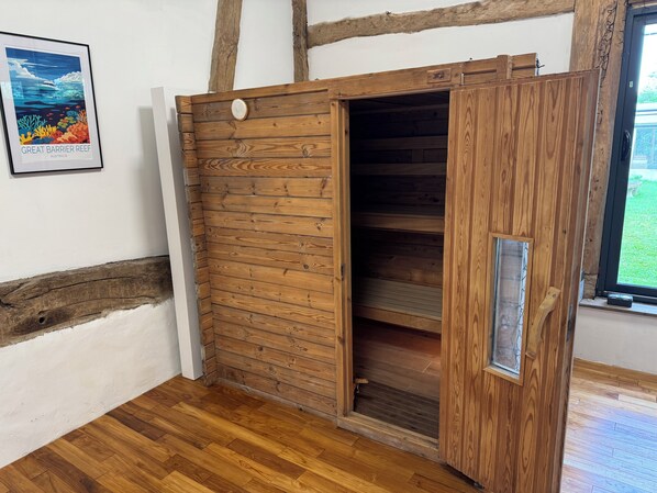 A wooden wardrobe with a sliding door in a room with wooden flooring and a framed picture on the wall.