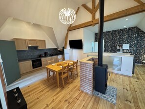 A modern kitchen with wooden cabinets, a dining table, and a black stove.