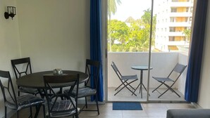 A room with a dining table and chairs, a sofa, and a balcony with a view of buildings and trees. - Fresher Breeze, your home from home in the heart of the beautiful Ocho Rios (St Anns)