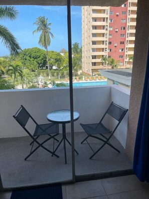 A balcony with a glass door, two black chairs, and a small round table. - Fresher Breeze, your home from home in the heart of the beautiful Ocho Rios (St Anns)