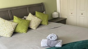 A neatly made bed with pillows, a rolled towel, and a green throw blanket. - Fresher Breeze, your home from home in the heart of the beautiful Ocho Rios (St Anns)