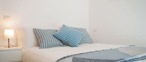 Ein Schlafzimmer mit einem Bett, Kissen, einer Nachttischlampe und einem Bild an der Wand.
