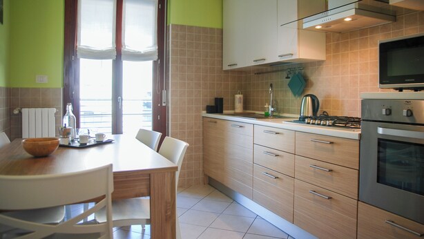 A kitchen with a dining table, chairs, cabinets, a stove, and a television. - Double Space Apartment - Milan - 6 guests · Airport · Train · Garage (Milano)