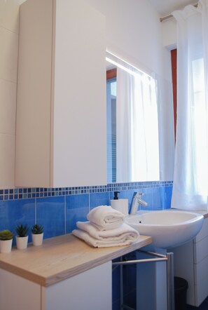 A bathroom with a sink, mirror, and towel stack. - Double Space Apartment - Milan - 6 guests · Airport · Train · Garage (Milano)