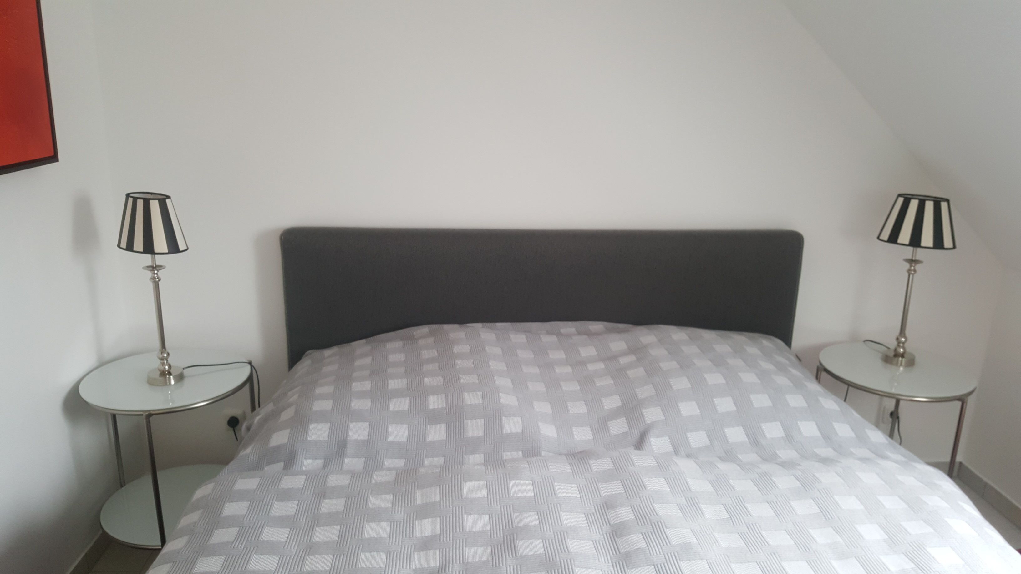 A bedroom with a bed, two bedside tables, and two lamps.