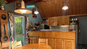 A wooden kitchen with a round dining table, wooden chairs, and a window with curtains. - Large house with a pool and spacious grounds in La Rochelle. (La Rochelle)