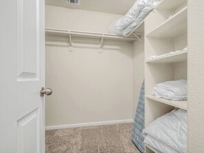 Um closet espaçoso com porta, cabideiro e prateleiras com toalhas dobradas.