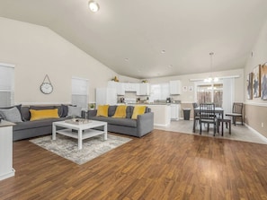 A modern living room with a grey sofa, white coffee table, and wooden flooring. - Amber Cove Cottage  3 BR  Sleeps 8 (Fresno)