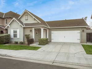 A two-story residential house with a garage, a covered front porch, and a well-maintained lawn. - Amber Cove Cottage  3 BR  Sleeps 8 (Fresno)