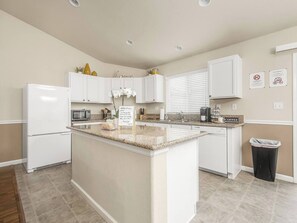 A modern kitchen with white cabinets, a granite countertop, and a central island. - Amber Cove Cottage  3 BR  Sleeps 8 (Fresno)