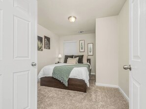 A bedroom with a bed, a window, and a door.