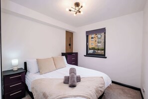 Een slaapkamer met een bed, nachtkastjes, een raam met uitzicht en een plafondlamp.