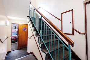 Eine Treppe mit türkisblauen Geländern und Holzhandläufen, die zu einer oberen Etage führt.