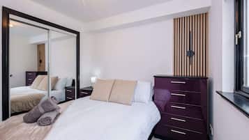 A bedroom with a bed, a dresser, a mirror, and a window.