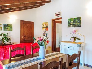 Ein Essbereich mit Holztisch, Stühlen, einem Blumenstrauß und Bildern an den Wänden.