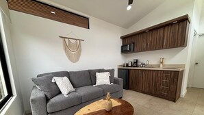 Uma sala de estar moderna com um sofá cinza, mesa de centro de madeira e armários de cozinha embutidos.