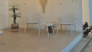 Quarto com ventilador de teto, decoração de sonho e duas cadeiras brancas.