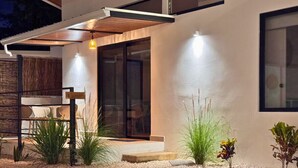 Uma área de piscina exterior moderna com design minimalista, incluindo uma pérgula, zona de estar e um jardim bem cuidado.