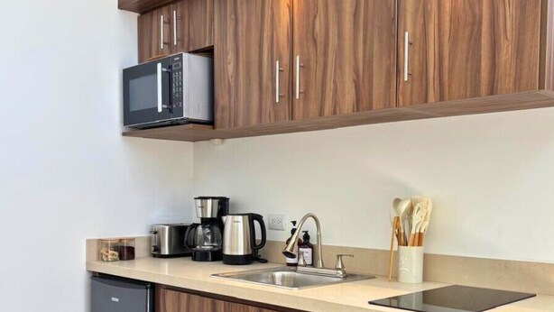 Uma cozinha moderna com armários de madeira, micro-ondas embutido, cafeteira e máquina de lavar louça.